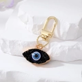 Golden Evil Eye keychain with blue resin center and black crystals on natural stones - Black Eye