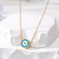 Detailed macro view of gold evil eye necklace on a textured white stone base - Sky Blue