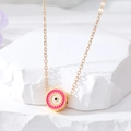 Close-up of pink enamel Evil Eye pendant with golden eyelashes on a fine gold chain - Rose Red