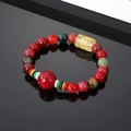 Macro shot of red agate beads with a yellow cylinder bead featuring etched Sanskrit symbols - Purplish Red Beads