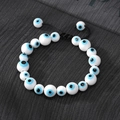 Adjustable evil eye beaded bracelet with white ceramic beads on a textured background - Ceramic Style / Blue White