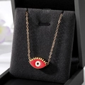 Détail macro du pendentif œil porte-bonheur en émail rouge avec cils dorés sur fond noir - Style de Cils Rouges
