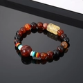Handmade beaded bracelet with agate, amber-colored bead and Buddhist mantra on black surface - Black Brown Beads