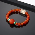 Vintage red agate beaded bracelet with engraved mantra bead on reflective black surface - Brown Beads