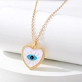 Primer plano del colgante de corazón dorado con ojo turco esmaltado y cadena de eslabones - Corazón Blanco Ojo Azul