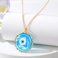 Macro detail of Turkish evil eye pendant with blue color gradients and golden wavy frame - Blue Round Eye