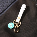 Detail of evil eye keychain with white leather strap and gold-tone hardware - Green Enamel Eye With Eyelashes (White Leather Strap)