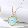 Elegant gold evil eye necklace with blue resin pendant displayed on white pedestals - Light Blue Round Eye