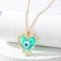Detail of gold evil eye heart necklace with blue enamel and pearls on white stand - Green