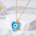 Detail der goldene Herzanhänger mit blauem Marmor Evil Eye Harz auf Steingrund - Blaues Herz