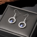 Silberne Evil Eye Ohrhänger mit funkelnden Strasssteinen auf einer Schmuckbox - Hohle Blaue Runde Augenohrringe (Silberner Haken)
