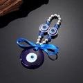 Etnische blauwe oog sleutelhanger met zijden strik en kralen op zwart oppervlak - Blauw Glazen Oog
