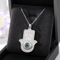 Détail du pendentif Main de Fatma argenté avec œil bleu sur coussin à bijoux noir - Œil Vert Grande Main De Fatima Argentée