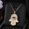 Macro view of gold Hamsa hand pendant with sparkling rhinestones and evil eye detail - Gold Black Diamond Eye