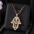 Close-up of a golden Hamsa Hand pendant with rhinestones on a black velvet box - Gold Hollow Hamsa