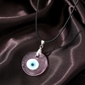 Macro shot of pink resin Evil Eye pendant with black wax cord on silk background - Transparent Pink