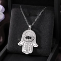 Detailed close-up of Hamsa Hand pendant with rhinestones and black eye on velvet - Silver Black Diamond Eye
