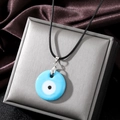 Detail of the blue glass Evil Eye pendant with clear textures and woven black rope chain - Sky Blue