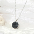 Detail van een zilverkleurige ketting met ronde hanger en donkerblauwe kristallen stenen - Zilvergrijs Rond (2)