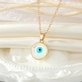 Elegant gold necklace featuring a classic blue Evil Eye circular pendant on silk background - Round / Round Evil Eye Necklace