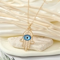 Détail du pendentif Main de Fatma et Œil du Mal sur collier doré avec design évidé vintage - Style Petite Main Œil Ovale