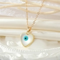 Detailed shot of a gold heart pendant with a blue evil eye and mother of pearl inlay - Heart Shape / Heart Eye Necklace