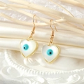 Elegant gold heart earrings with blue evil eye stone and opal finish on silk background - Heart Shape / Heart Evil Eye Earrings