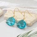 Elegante geometrische aquablaue Kristallohrringe mit Goldhaken auf cremefarbenem Stein - See Blau