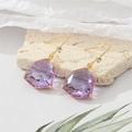 Nahaufnahme von lavendelfarbenen Kristallohrringen mit Goldhaken und kleinen Diamantakzenten - Lila
