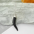 Gros plan d'un pendentif cornicello noir brillant sur une chaîne à billes argentée - Piment Noir