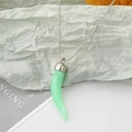 Gros plan d'un pendentif en résine vert clair en forme de corne avec texture marbrée sur chaîne argent - Piment Vert Clair