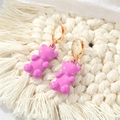 Dettaglio degli orecchini a forma di orsetto rosa con cerchi dorati su fondo bianco - Orso Viola