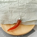 Détail d'un pendentif piment en résine orange translucide sur une chaîne à billes - Piment Brun Rouge