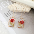 Detail of handmade resin earrings featuring red dried flowers and pearls on marble - Red Flower (With Pearl)
