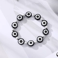 Bracelet rétro œil de protection avec perles en métal argenté sur un fond minimaliste - Perles Argentées Œil Noir