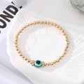 Detailed close-up of a golden beaded Evil Eye bracelet with green crystal accents and rhinestones - Green Round Eye