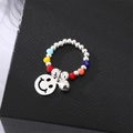Close-up of a colorful beaded ring with silver balls and a smiley face bell charm - Smiley Face Ring