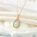 Macro-opname van de mintgroene evil eye ketting met goudkleurige pavé kristallen - Lichtblauwe Ketting