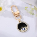 Detail eines goldenen Evil Eye Schlüsselanhängers mit blauer Emaille und Strasssteinen - Schwarzes Emaille Wimpernauge mit Strass