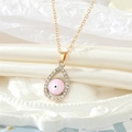 Detailopname van de roze Evil Eye druppelhanger met gouden afwerking en glanzende strass - Roze Ketting