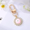 Close-up of golden evil eye sun keychain with pink enamel and sparkling rhinestones - Pink Enamel Round Eye With Rhinestone