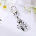Detail of vintage silver skeleton hand keychain accessory with daisy prop decor - Devil's Claw