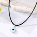 Dettaglio macro della collana con ciondolo Malocchio, bordo argento e cordino nero - Bianco
