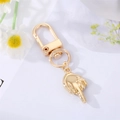 Detailed view of a gold-plated astronaut middle finger gesture keychain with D-ring clasp - Middle Finger Gesture