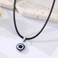 Zilveren Evil Eye hanger ketting op zwart koord tegen een getextureerde steen achtergrond - Saffierblauw