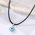 Blauwe Evil Eye hanger ketting met zilveren rand en zwart lederen koord op witte steen - Meerblauw