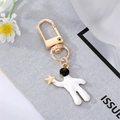 Golden astronaut keychain with white enamel details and star charm for bag accessories - Astronaut Raising Star