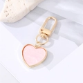 Dettaglio macro di un portachiavi a forma di cuore con trama in marmo rosa e telaio in oro lucido - Cuore con Patch Rosa