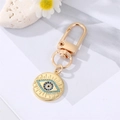 Macro shot of evil eye keychain with blue crystals and gold finish on white background - Round Base Blue Crystal Eye