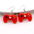 Detail shot of a red game controller earring showing black buttons and white heart pattern - Red